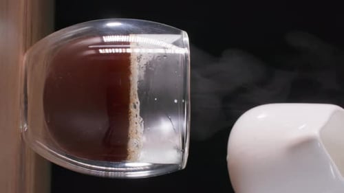 Milk Being Poured Into Steaming Mug of Coffee