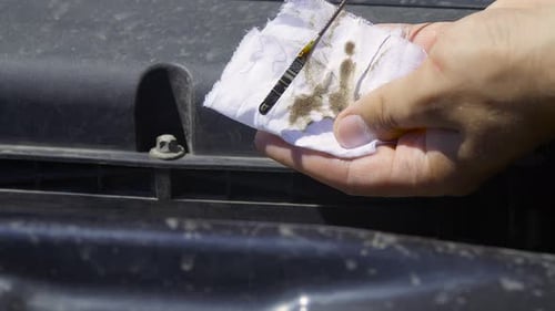 Hand Checking Car Engine Oil with Dipstick