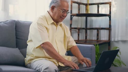 Senior Man Typing on Laptop in Living Room