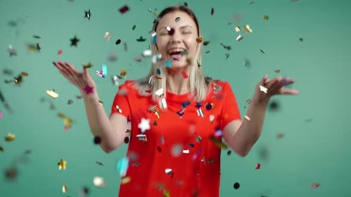 Excited Woman Applauding Having Fun Rejoices Over Confetti Rain in Green Studio