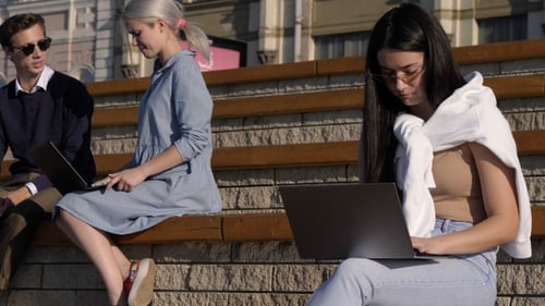 Multiethnic students sitting outside the university talking