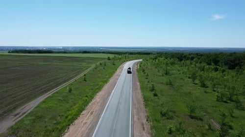 aerial view flight over the road with cars. green fields and trees on the sides of the road.