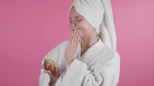 Beautiful Woman Applying Lotion to Face after Shower