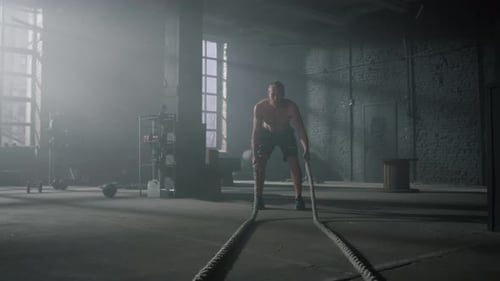 Man Working Out with Battle Ropes in Gym