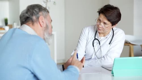 Doctora caucásica concentrada seria que escucha las quejas de los pacientes masculinos Escribir los síntomas