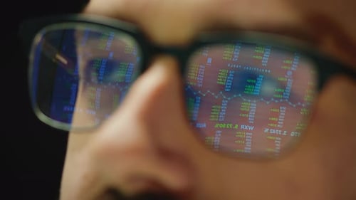 Close Up Reflection of Stock Market Graphs in Broker Glasses