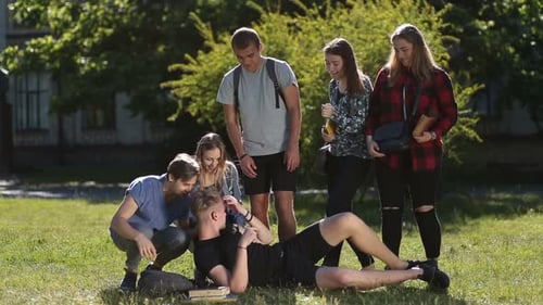 Group of Students Waking Up Sleepy Friend in Park