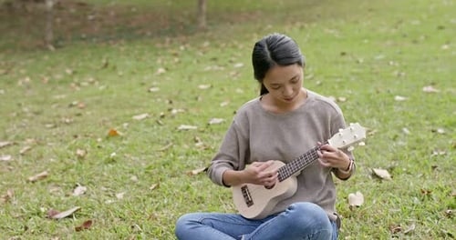 Woman play on ukulele at the park