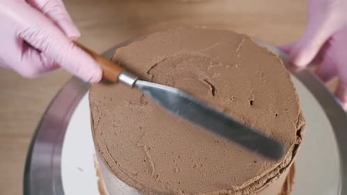 Pastry Chef Decorating Cake With Chocolate Frosting