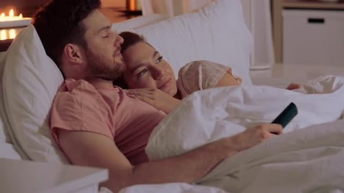 Happy Couple Watching Tv in Bed at Night at Home