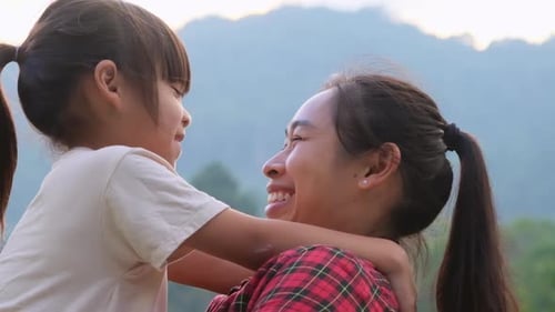 Happy little daughter hugs and kisses her mother in the park. family relationship concept