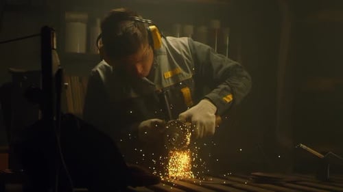 Skilled Metalworker Grinding Metal in Dark Workshop