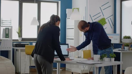 Man and Woman Analyze Data Together in Office