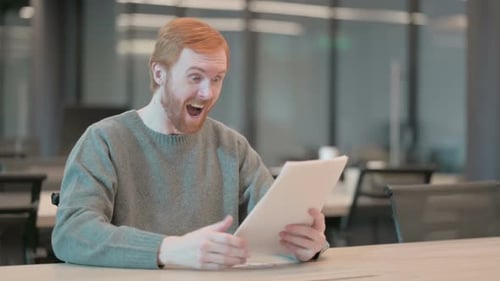 Young Man Celebrating Success While Reading Documents in Office