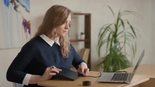Woman Uses Drawing Tablet with Laptop at Home