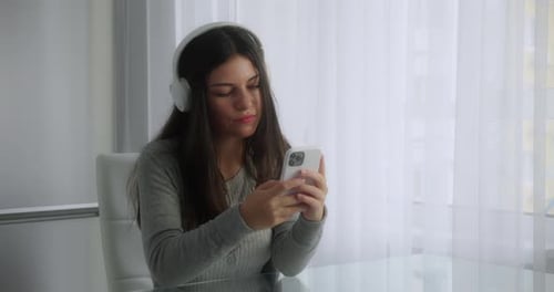 Woman with Headphones Using Smartphone Indoors at Desk