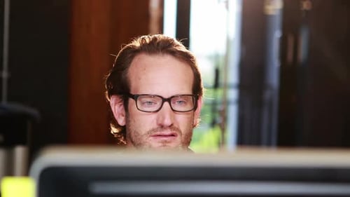 Man with Glasses Working at Computer in Office
