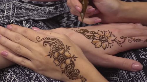 La mujer está decorando manos por Henna Tattoos