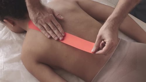 Medical Professional Applying Therapeutic Tape to Back