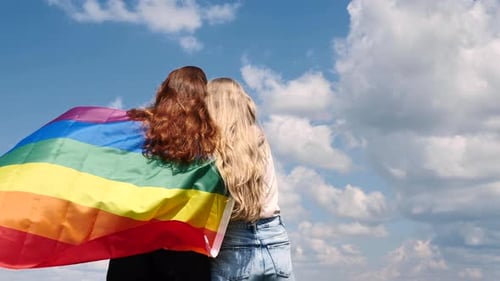 Affectionate Couple Embrace with Rainbow Flag on Sunny Day