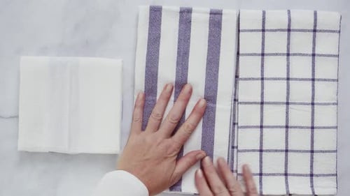 Hands Folding White and Purple Dish Towels