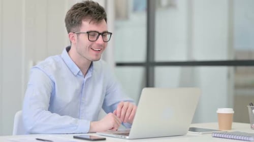 Young Man Attends Video Call at Work