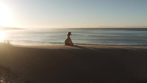 Woman Dancing In Long Dress On Sandy Beach