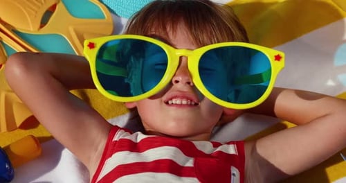 Boy Lying on Beach Towel with Sunglasses