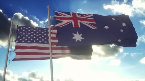 American and Australian Flags Waving in Wind Against Blue Sky