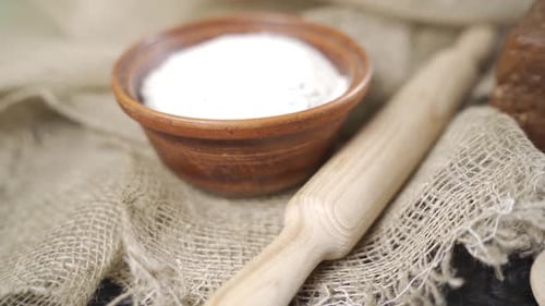 Flour in a Clay Plate and a Wooden Rolling Pin Closeup