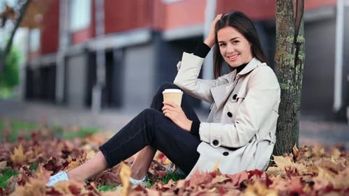 Female Sitting Near Tree with Yellow Autumn Foliage at Park