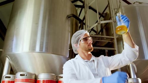 Man Inspecting Liquid Sample in Industrial Setting