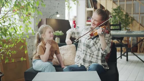 Woman Playing Violin With Child in Living Room