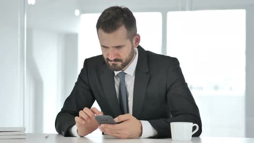 Man in Suit Using Smartphone at Office Desk