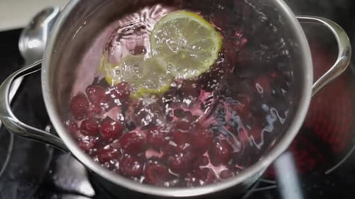 Boiling Berries and Lemon Slices in Pot