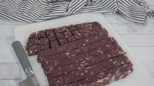 Zeitraffer. Schritt für Schritt. Hausgemachten Macadamia-Fudge auf einem weißen Schneidebrett schneiden