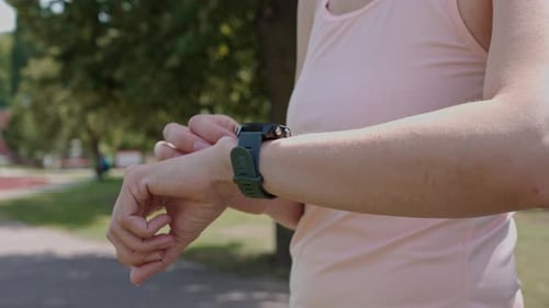 Woman Adjusting Fitness Watch in a Park