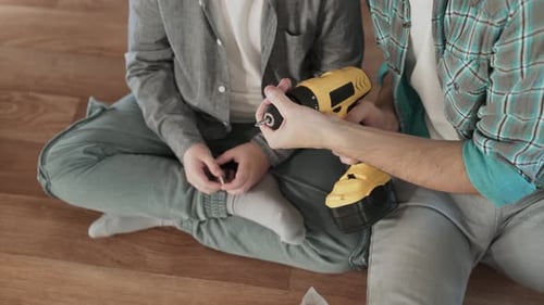 Child and Adult Assembling Furniture with Electric Drill