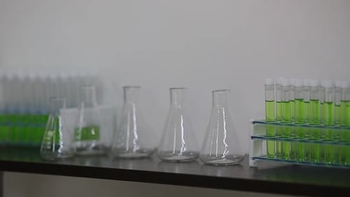 Une main de femme pose des tubes à essai sur une étagère dans un laboratoire
