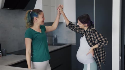 Mulher grávida e sua mãe na cozinha se divertem e dançam