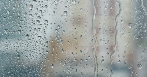 Rain Drops Trickling Down Window on Rainy Day