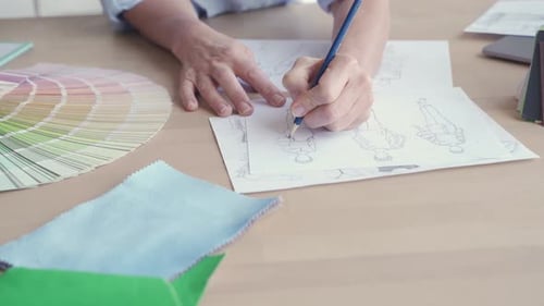 Female Fashion Designer Drawing Sketches on Table Close Up View