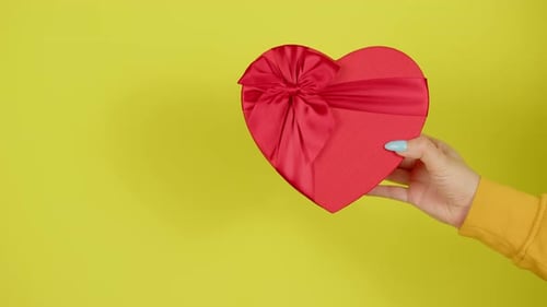 Close Up of Hand Holding Heart Shaped Gift