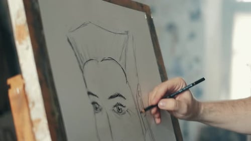 The Artist Is Working on a Painting on the Easel in the Workshop with a Pencil