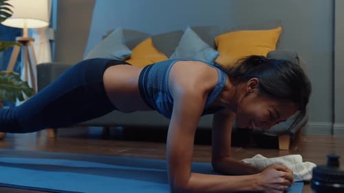 Mujer asiática en ropa deportiva haciendo ejercicio y usando el teléfono para ver un vídeo tutorial de yoga.