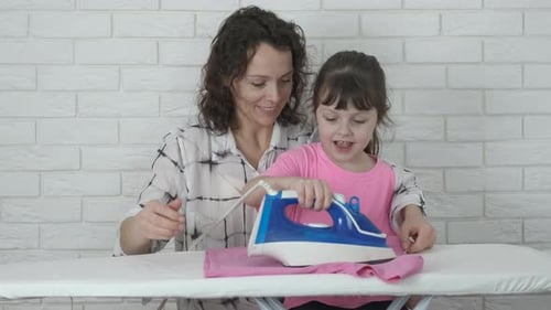 Woman and Child Ironing Clothes Together at Home