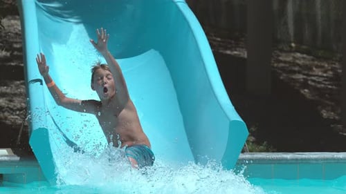 Boy Rides Water Slide into Swimming Pool