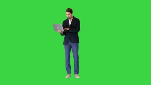 Young Standing Business Man Working on a Laptop on a Green Screen Chroma Key
