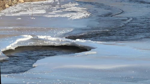 Natureisbrücke über Fluss, der durch Eisschollen fließt
