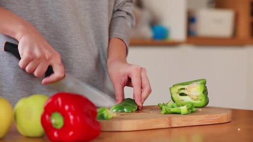 Woman Cutting Green Bell Peppers on Cutting Board